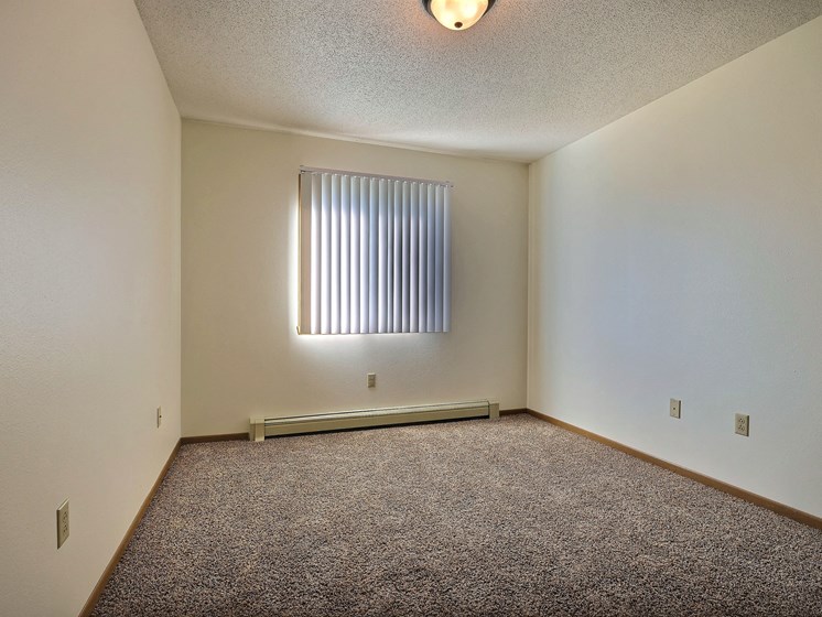 a spacious bedroom with carpet and a window. Fargo, ND Sterling Park Apartments